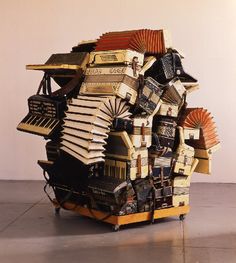 an art piece made out of books and musical instruments on top of each other in front of a white wall