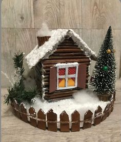 a small house made out of wood and fake snow with a christmas tree in the window