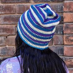 a woman with long black hair wearing a blue and white striped knitted beanie