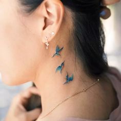 a woman's neck is adorned with three blue birds on the back of her neck