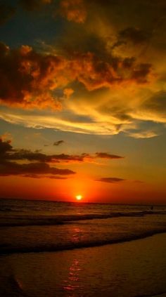 the sun is setting over the ocean with clouds