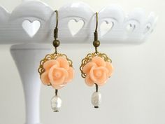 "A pretty peach resin cabochon rose flower is set onto lace edged filigree settings with a beautiful white freshwater pearl that dangles below.  Pretty feminine design.    The peach resin cabochon rose, size - 14 x 13mm  White freshwater pearl, size - 5 x 7mm  Raw brass filigree settings  Bronze tone earring wire - Nickel and lead free.  Earrings measure 1.75\" approx. in length including the ear wire.   ★ All items arrive in a gift box with ribbon.  Ready to ship.  Personalized messages and direct shipping to the recipient available on request.  ★ If you would like more than 1, please convo me.  I offer discounts for multiple purchases.   Please read my shop policies for details on shipping, delivery etc.  https://www.etsy.com/Littlemissjdesigns/policies  ♥ ♥ ♥ Visit my boutique for more Elegant Orange Flower Earrings For Gift, Delicate Peach Jewelry For Gifts, Elegant Adjustable Apricot Jewelry, Elegant Adjustable Rose Design Earrings, Peach Flower Shaped Jewelry For Gift, Peach Flower-shaped Jewelry For Gift, Rose Colored Dangle Flower Earrings For Wedding, Vintage Rose Gold Flower Earrings For Wedding, Rose Dangle Flower Earrings For Wedding