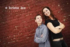 two people standing next to each other in front of a brick wall with the words krista lee photography on it