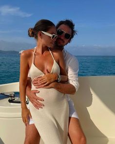 a man and woman in bikinis on a boat with the ocean in the background