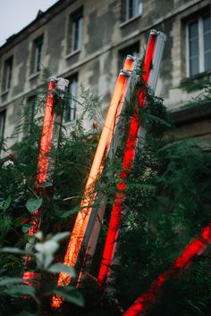 red lights are shining on the tall poles in front of an old building and trees