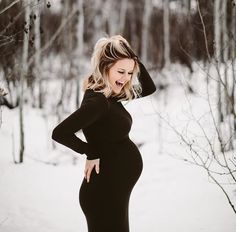 a pregnant woman standing in the snow with her hands on her hips