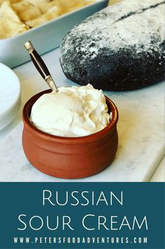 russian sour cream in a bowl with a spoon on the counter next to some bread