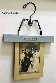 an old photo hanging on a wall with clothes pins attached to it and a hanger that says, organized clutter