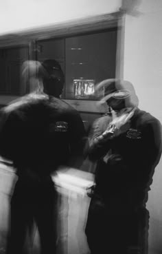 black and white photograph of two police officers talking to each other in front of a counter