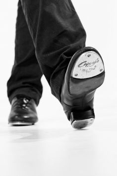 black and white photograph of someone's foot with a golf club in their shoe