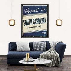 a living room with a blue couch and coffee table in front of a poster that says home is south carolina