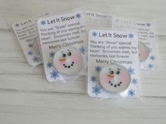 three snowman magnets in plastic bags on top of a white table with blue snowflakes