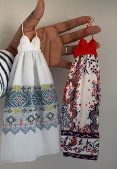 two handmade towels hanging from hooks on the wall, one with a red and white top