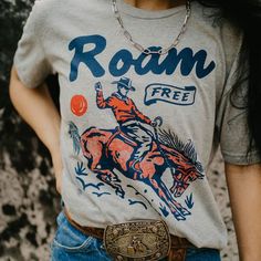 Show off your wild side in this Roam Free Graphic Tee! A basic grey tee with a fun, vibrant graphic of a bronc rider is a must for any rodeo lover's wardrobe. Vintage Graphic Design Tee, Graphic Tee Ideas, Western Tee Shirts, Bronc Rider, 1st Rodeo, Western Tee, Casual Bodysuit, Western Graphic Tees, Camp Ideas