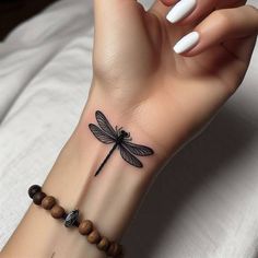 a woman's wrist with a dragonfly tattoo on it