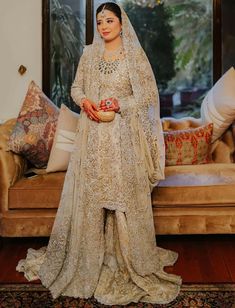 a woman in a bridal outfit standing next to a couch