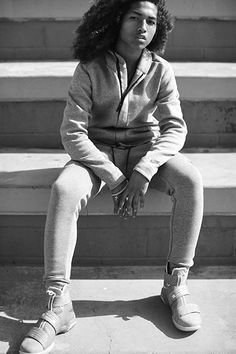 a black and white photo of a young woman sitting on steps with her legs crossed