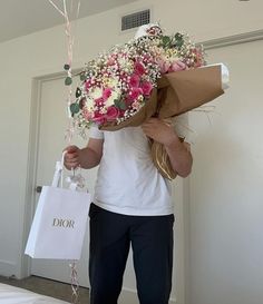 a man holding a bouquet of flowers in front of his face while standing next to a door