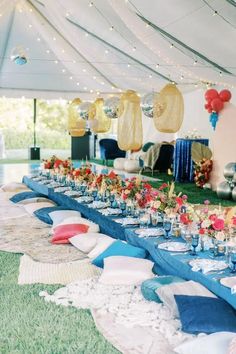 a long table is set up with blue linens and red flowers