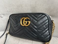 Overview Gucci GG Marmont small shoulder bag in black chevron matelassé leather with gold hardware. This small Marmont chain camera style bag has a softly structured shape and zip top closure. Effortlessly chic and sophisticated, this style can be both with a casual outfit or for evening wear. Suitable for both day to day or occasion wear and ideal for those who prefer a cross body option. Features Black Chevron Matelasse Leather Double G antique gold-toned hardware Interior slip pocket Zipper pocket with long zipper pulls Made in Italy Microfibre lining with a suede like finish Adjustable chain shoulder strap with leather detail Condition Exterior: Good to very good condition with small signs of wear. There are small marks to the leather and some scuffing to corners. Interior: Good condit Gg Marmont Small Shoulder Bag, Gucci Gg Marmont, Black Chevron, Gg Marmont, Small Shoulder Bag, Casual Backpack, Zip Top, Casual Outfit, Evening Wear