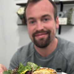 a man holding a sandwich with lettuce and tomato on it in front of him