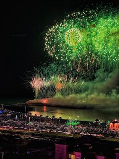 fireworks are lit up in the night sky over a city and water with buildings on both sides