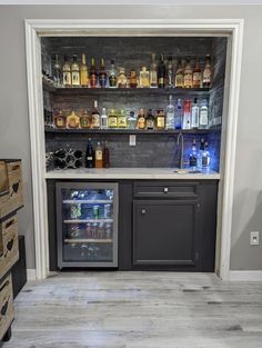 an empty bar with liquor bottles on the shelves and behind it is a mini fridge