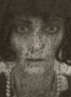 a black and white photo of a woman's face with lace covering her eyes