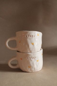 three ceramic cups with the words honey and honey written on them, all stacked together