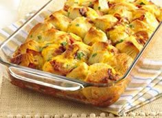 a casserole dish with meat and cheese in it on a glass tray next to a serving utensil