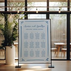 a table plan sitting on top of a wooden floor next to a potted plant