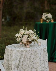 a table with flowers and candles on it is set up for an outdoor wedding reception