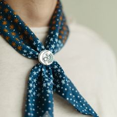 a woman wearing a blue scarf with white stars on it and a button in the center