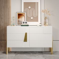 a white dresser with gold accents in a living room next to a framed art print