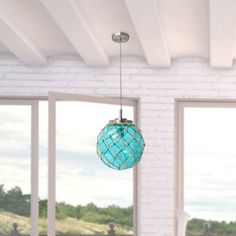 a blue glass ball hanging from a ceiling in a room with white brick walls and windows