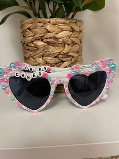 the sunglasses are decorated with pink and blue beads, which spell out'cheers '