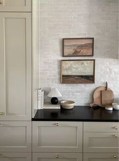 a kitchen with white cabinets and black counter tops in front of a painting on the wall