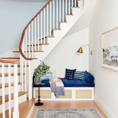 there is a blue couch under the bannister in this room with white walls