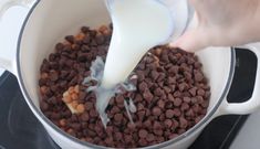 a person pouring milk into a pot filled with chocolate chips