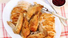 a white plate topped with sliced chicken next to a bowl of cranberry sauce