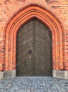 an old brick building with a large wooden door and arched doorway that leads into the courtyard