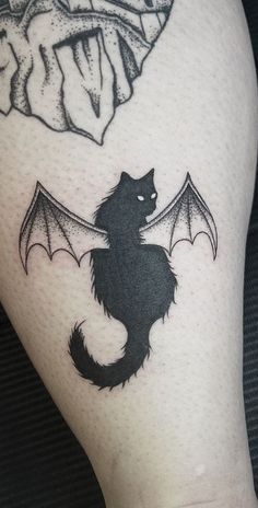 a black and white photo of a cat with a bat tattoo on it's leg