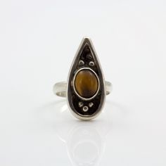 Discover the perfect blend of celestial charm and earthy elegance with our stunning Teardrop Tiger's Eye Ring. This unique piece features an 8x10mm oval Tiger's Eye cabochon, set in a sleek sterling silver band. The teardrop shape of the ring enhances the natural beauty of the Tiger's Eye, with its mesmerizing golden-brown hues and captivating chatoyancy. Ideal for those who love boho chic and earthy jewelry, this size 6.5 ring brings a touch of cosmic allure to any outfit. Whether you're dressing up for a special occasion or adding a statement piece to your everyday wear, this ring offers a sophisticated and versatile option. The sterling silver setting complements the rich tones of the Tiger's Eye, creating a piece that feels both luxurious and grounded. Embrace the beauty of the univers Brown Oval Gemstone Jewelry, Brown Teardrop Sterling Silver Jewelry, Brown Sterling Silver Teardrop Jewelry, Elegant Cabochon Teardrop Ring, Elegant Teardrop Cabochon Ring, Brown Teardrop Gemstone Jewelry, Elegant Teardrop Natural Stone Rings, Earthy Rings, Earthy Elegance