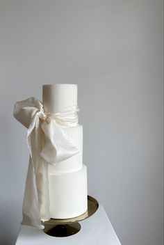 a three tiered white wedding cake with a bow on top