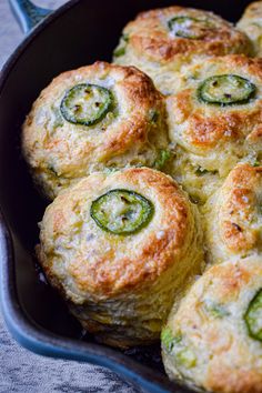 some food is in a black pan on a tablecloth and it looks like broccoli rolls