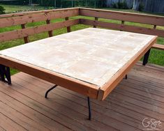 a wooden table sitting on top of a wooden deck next to a fence and grass