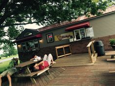 two people sitting on picnic benches in front of a restaurant