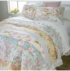 the bed is made with floral comforters and pillows