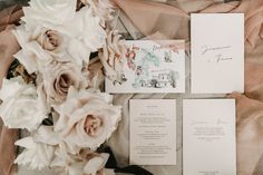 the wedding stationery is laid out with flowers