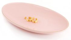 a pink plate with two gold earrings on it